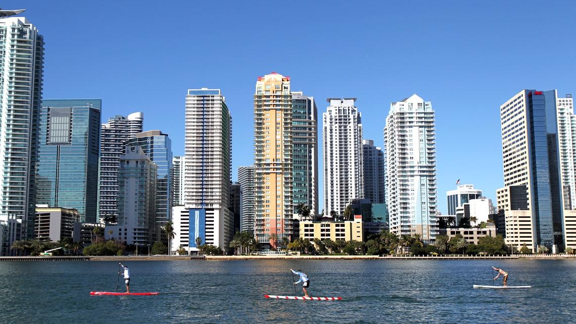 Although monthly home sales prices fell again in September in Miami-Dade County, price tags remain higher than year-ago levels. Above: People ride paddleboards past Brickell, the county’s financial district.