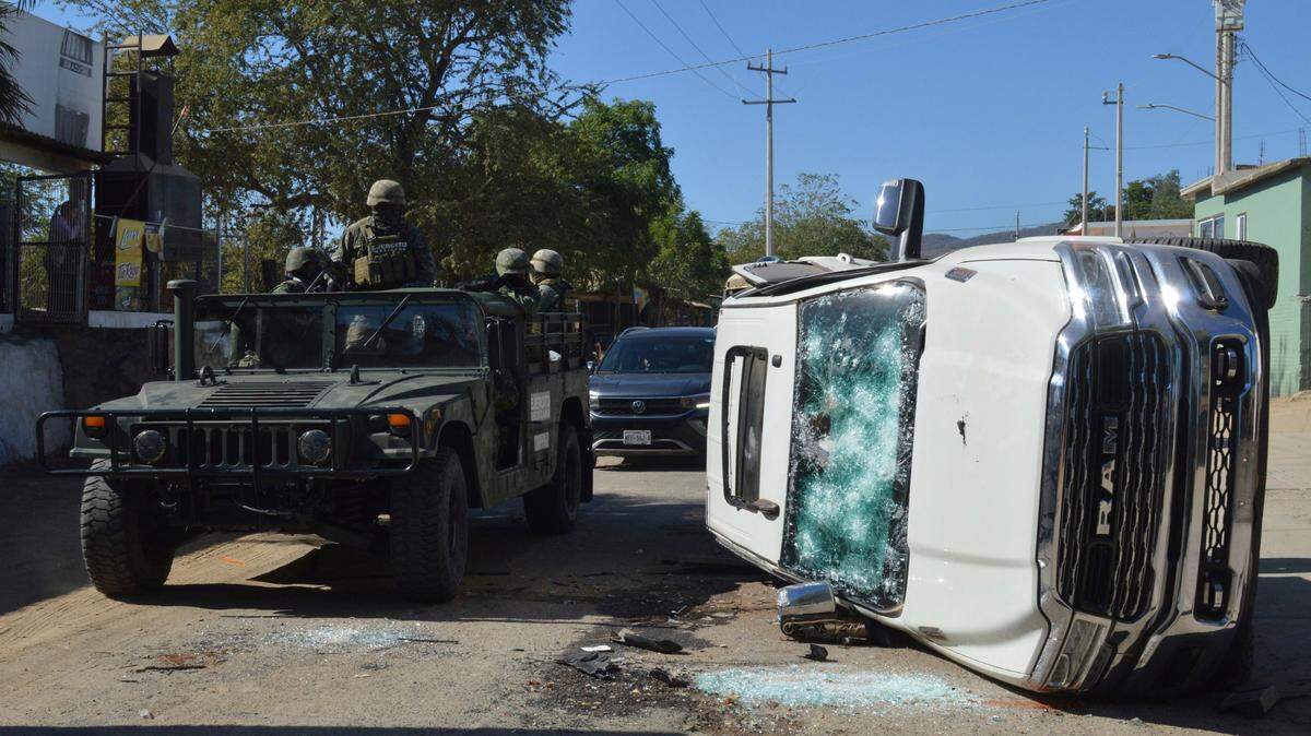 SOLDADOS DEL ejercito MEXICANO pasan junto a un vehículo destruido en las calles de Jesús María, México, el sábado 7 de enero de 2023, el pueblo donde Ovidio Guzmán, el hijo de El Chapo, fue detenido después de un tiroteo que mató a 10 militares y 19 presuntos miembros del cartel de la droga de Sinaloa(AP Photo/Martin Urista)