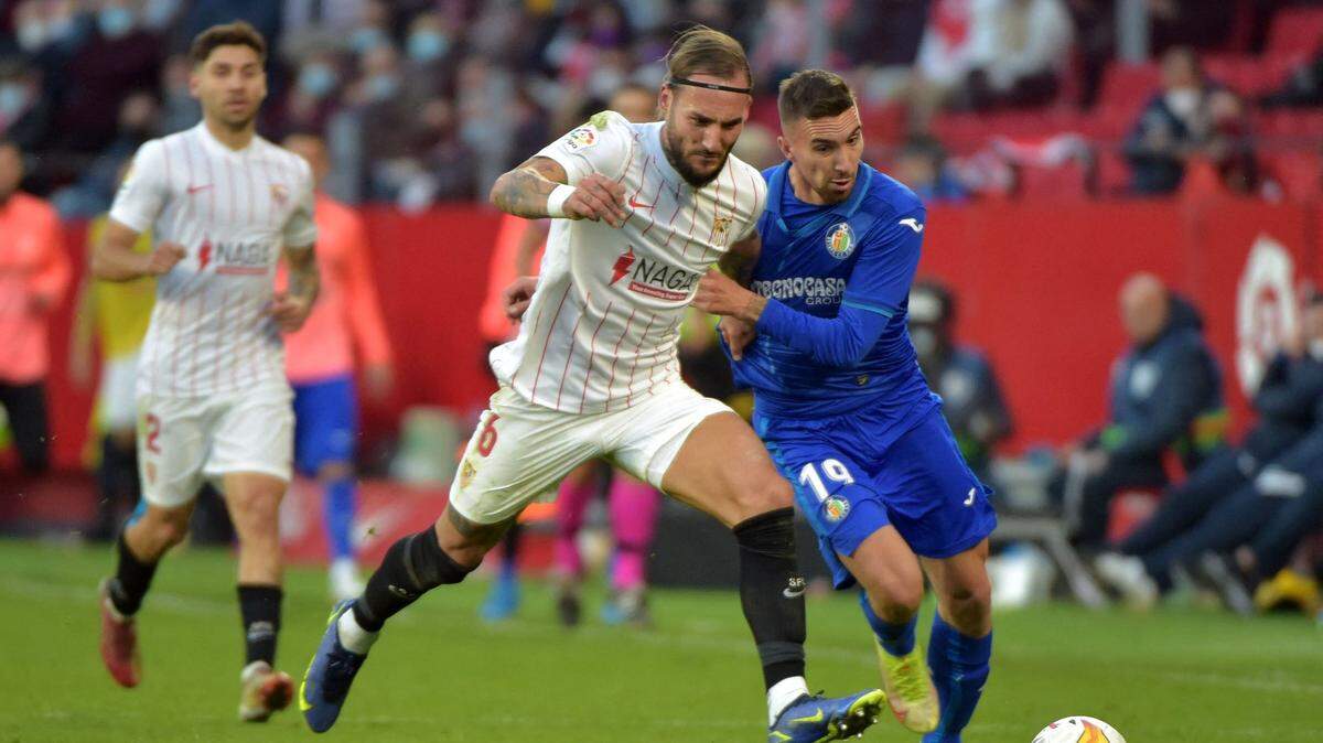 El delantero del Getafe Dario Poveda (der.) lucha por la pelota con Nemanja Gudelj, del Sevilla, en el partido de la liga española celebrado el 9 de enero de 2022 en Sevilla.