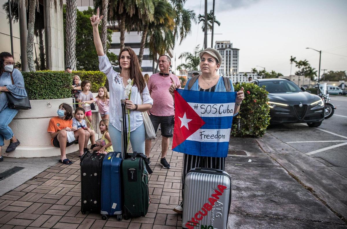 Cuban exiles Alondra Milan’s ( left) and Adalixis Alamaguer carried their luggages in solidarity with activist Anameli Ramos who is stranded in Miami after she was denied boarding an AA flight to Havana,during a pacific march from the Cuban restaurant Versailles to the American Airlines offices in Coral Gables, on Friday February 18, 2022,