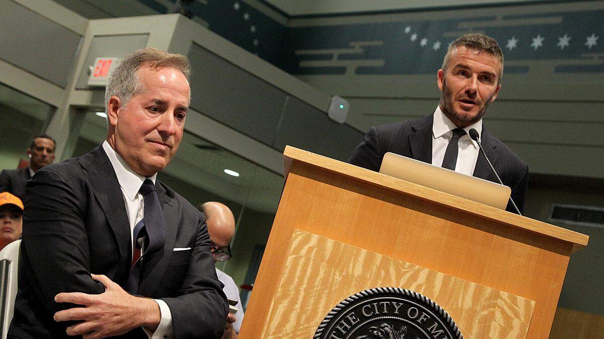 Jorge Mas (izq.) escucha a David Beckham en su presentación en la Comisión de Miami, el 12 de julio de 2018.