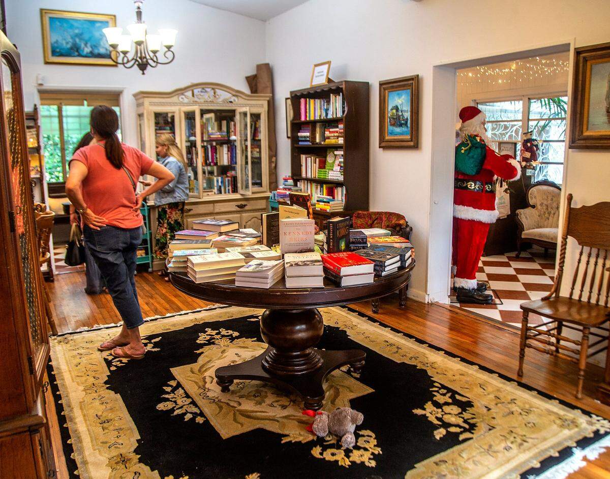 Los visitantes chequean libros en Sweet Haven Book Store, que en lugar de anaqueles, los exhibe en muebles de madera antiguos.