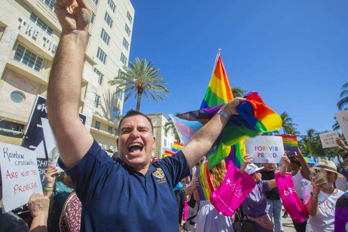 El comisionado de la ciudad de Miami Beach, Alex Fernández, ondea una bandera junto a manifestantes que portaban banderas arcoíris y carteles con los lemas “Miami Beach Orgulloso por Siempre” y “No Será Borrado” durante la Marcha Orgulloso por Siempre en Ocean Drive, Miami Beach, Florida, el domingo 31 de agosto de 2025, celebrada después de que las autoridades estatales ordenaran la eliminación del cruce peatonal del Orgullo LGBTQ de la ciudad. Alexia Fodere para The Miami Herald