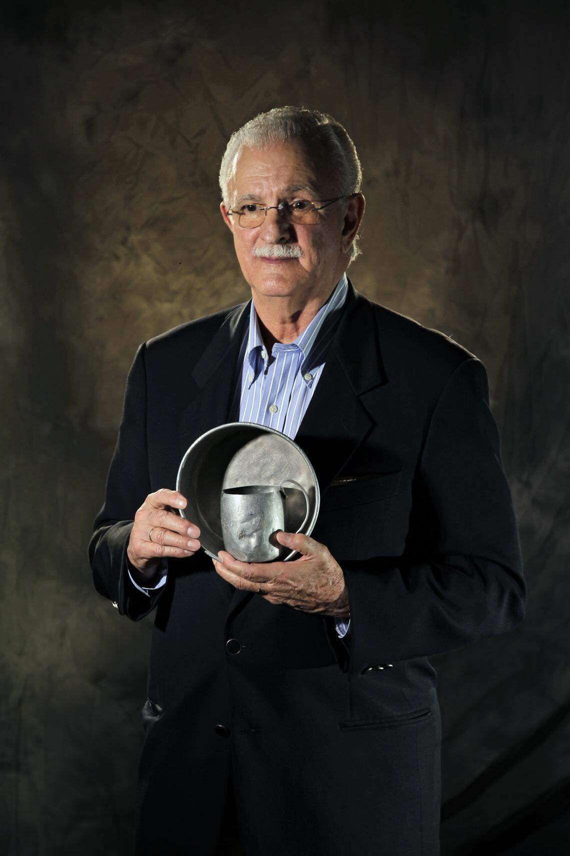 Eduardo Zayas-Bazan holds the tin cup and tin plate he used while in captivity in Cuba. He is a member of the Bay of Pigs Veterans Association, Brigade 2506 