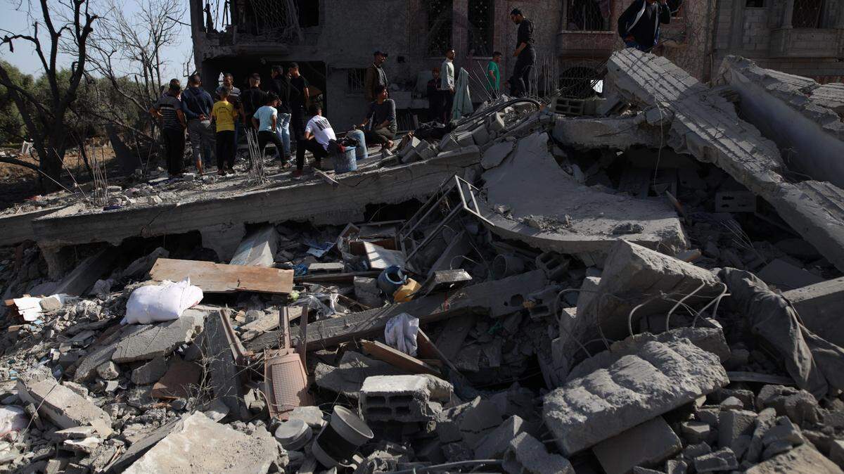 Un grupo de personas observa un edificio destruido por un bombardeo israelí, en el campo de refugiados Maghazi, en la región central de Gaza, el domingo 31 de marzo de 2024.