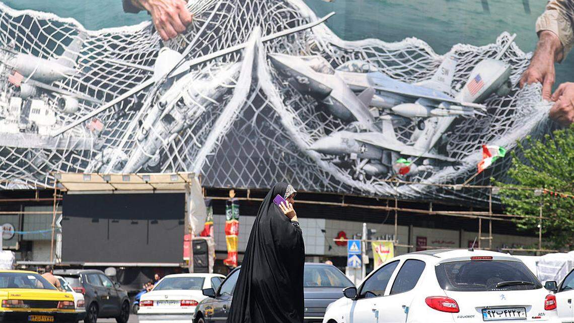 Una mujer pasa frente a una valla publicitaria gigante que dice “El estrecho de Ormuz permanece cerrado” en la Plaza de la Revolución, en Teherán, el martes 28 de abril de 2026.