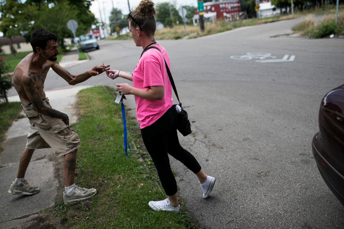Darcy Shepherd, a peer supporter who works with the Getting Recovery Options Working initiative, offers a cigarette to a man struggling with addiction in Dayton, Ohio, Oct. 3, 2018. Fatal drug overdoses have plunged more than 50 percent in Dayton from 2017, when the city had one of the highest opioid death rates in the nation. (Maddie McGarvey/The New York Times)