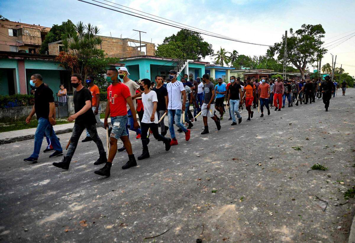 Un grupo de personas con palos en la mano participan en una manifestación en apoyo del gobernante cubano Miguel Díaz-Canel en el municipio de Arroyo Naranjo, La Habana, el 12 de julio de 2021.