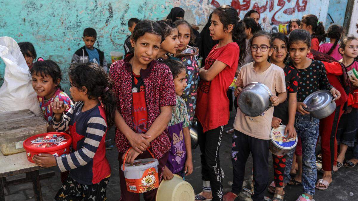 Decenas de niños palestinos hacen fila para recibir comida preparada por voluntarios que ayudan a las personas desplazadas del norte de Gaza, en donde ocurren los enfrentamientos entre tropas israelíes y militantes de Hamas, el jueves 9 de noviembre de 2023, en Rafah, sur de Gaza.