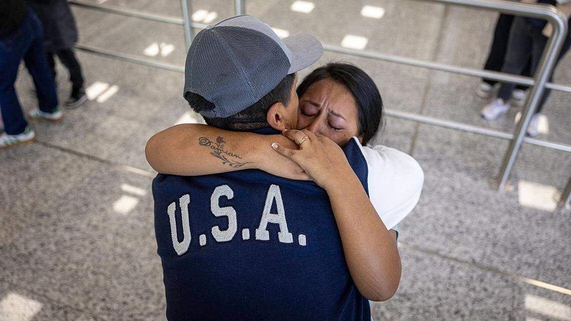 QUITO, ECUADOR - OCTOBER 27: Andrea, 28, embraces her husband Jorge at the Mariscal Sucre International Airport in Quito, Ecuador on October 27, 2025 after an overnight flight from New York City. She made the decision to "self deport" with their children after Jorge was detained by U.S. Immigration and Customs Enforcement (ICE) agents and later deported to Ecuador due to his undocumented status. Andrea, unable to work and care for her children without spousal support, chose to return to Ecuador with the help of an aid group, whose donors purchased their air tickets to Quito and volunteers assisted with the logistics of moving. In December of 2022 Andrea, Jorge and their daughter Jazlyn then age 3, made the arduous journey from South America north through the Darien Gap, where their large group was robbed by armed bandits, she said, while en route to the U.S.-Mexico border. There they crossed from Ciudad Juarez into El Paso, Texas and traveled to New York City. After first living 6 months in various NYC shelters, they briefly moved to Queens before relocating to Danbury, Connecticut where her sister's family had settled. During the nearly three years they lived in the U.S. they were able to work as day laborers in construction, sending some $6,000 back to Ecuador to partially construct an additional floor onto her mother's hillside family home in the poor and crime-challenged southern part of Quito, the nation's capital. The family has returned home larger than when they left, with the addition of baby Shanell, 7 months, born in Danbury as a U.S. citizen. Now every morning in Quito they check the skies before heading out to ply the same profession, selling umbrellas, they had left behind. They are still paying off the $2,000 of remaining debt they took on for the journey to chase their American Dream. (Photo by John Moore/Getty Images)