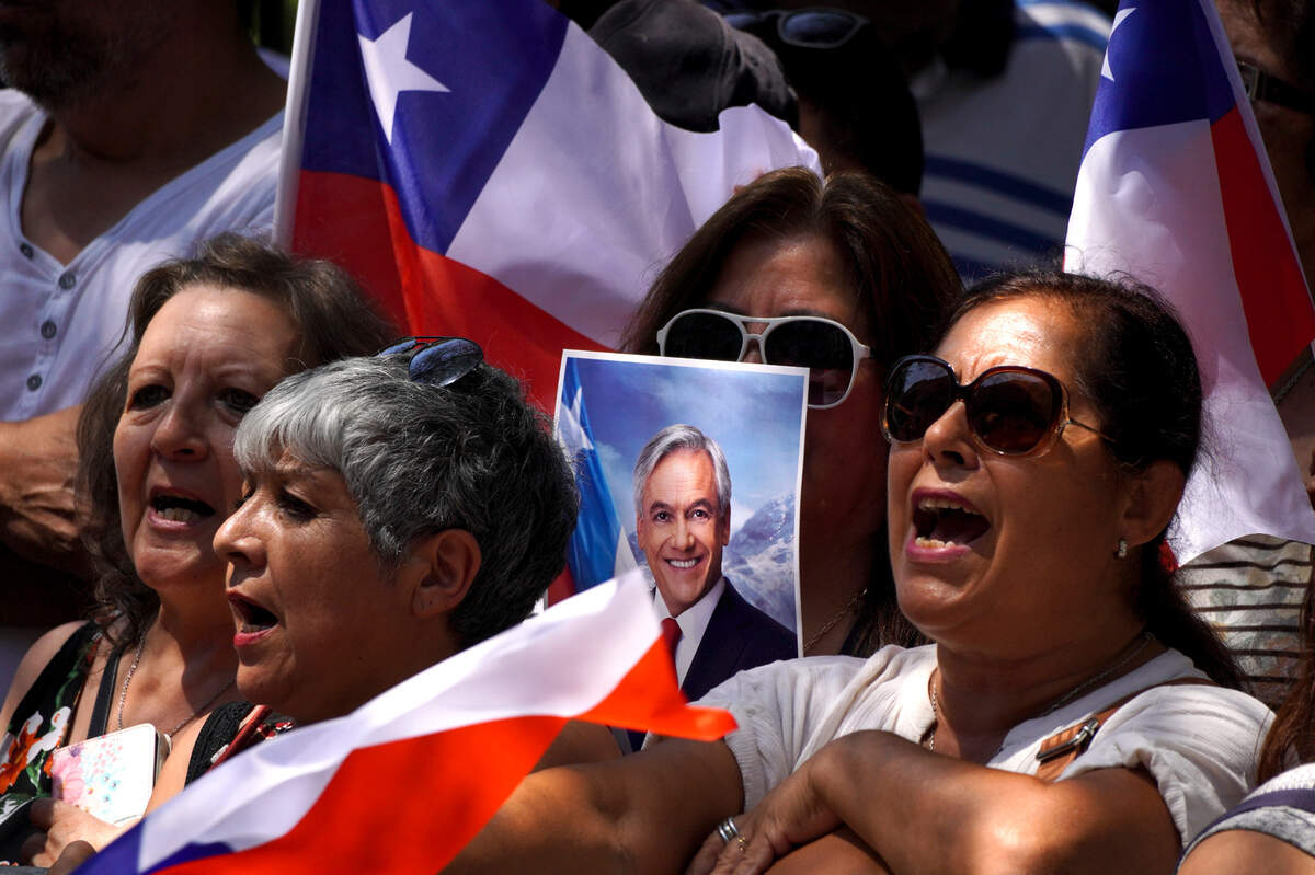 Una multitud canta el himno nacional frente a la sede del Congreso mientras espera la llegada de los restos del expresidente chileno Sebastián Piñera, en Santiago, el miércoles 7 de febrero de 2024.
