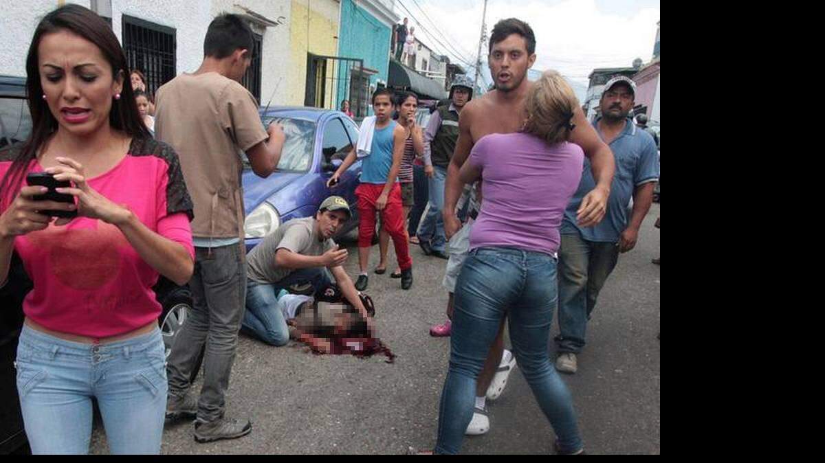 Algunas personas observan al estudiante venezolano, Kluiverth Roa, de 14 años, tras caer luego de recibir un impacto de bala en su cabeza, durante una manifestación el martes en San Cristóbal, Venezuela. 
