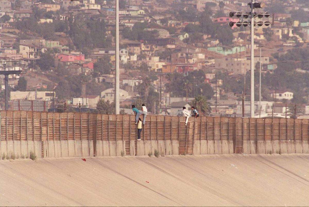 Los migrantes mexicanos saltan la cerca fronteriza a los Estados Unidos a lo largo de la frontera sur, cerca de Tijuana, en esta foto de archivo de noviembre de 1991. El viernes 12 de enero de 1996, la procuradora general Janet Reno dijo que cientos de agentes de la ley adicionales y equipos de avanzada se desplegarían a lo largo de la frontera entre California y Arizona a partir de la semana siguiente para controlar un aumento de la inmigración desde México.