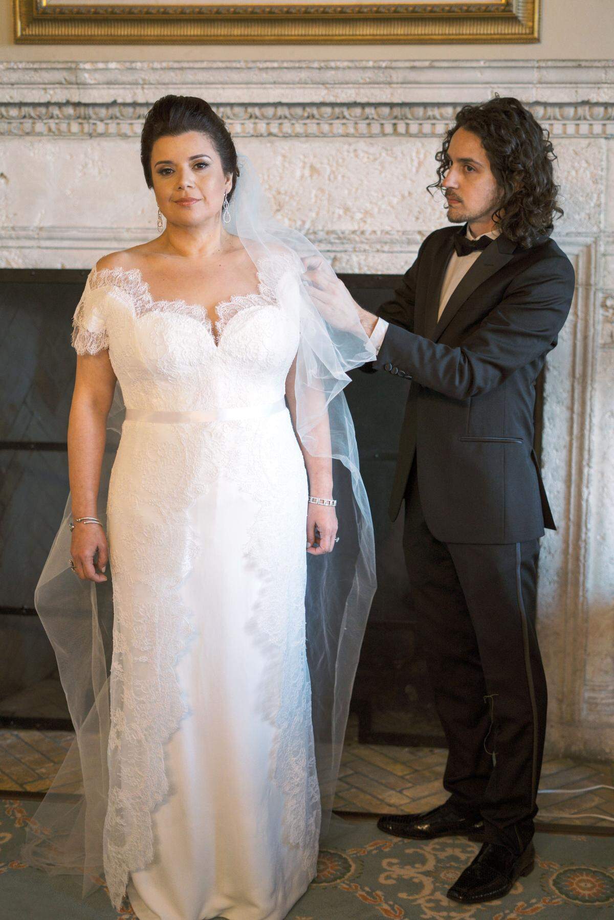 El diseñador Luis Escudero última los detalles del traje de novia de la analista política Ana Navarro, quien se celebró su boda con Al Cárdenas en marzo en Miami Beach. El vestido de crepé de seda destaca por el escote profundo y los detalles en encaje guipur.