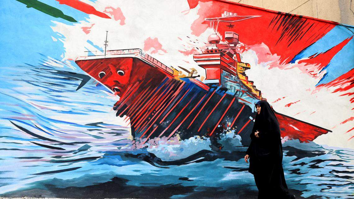 Una mujer pasa junto a un mural antiestadounidense y antiisraelí en Teherán el 21 de abril de 2026, en medio de un alto el fuego en la región.