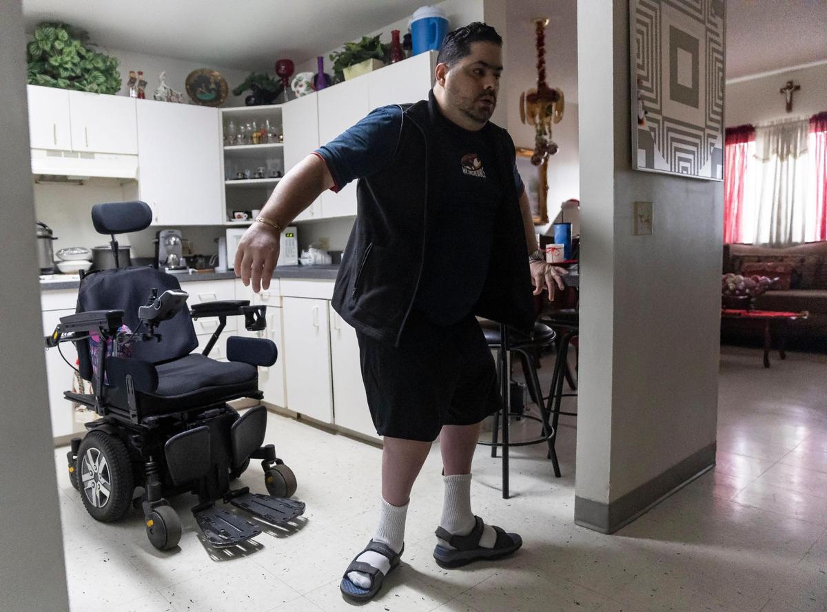 Rudens Rodríguez, de 43 años, intenta caminar hacia su habitación el miércoles 29 de noviembre de 2023 en Hialeah, Florida. Rodríguez sufre de Mielomeningocele, la forma más grave de espina bífida, que afecta su movilidad.