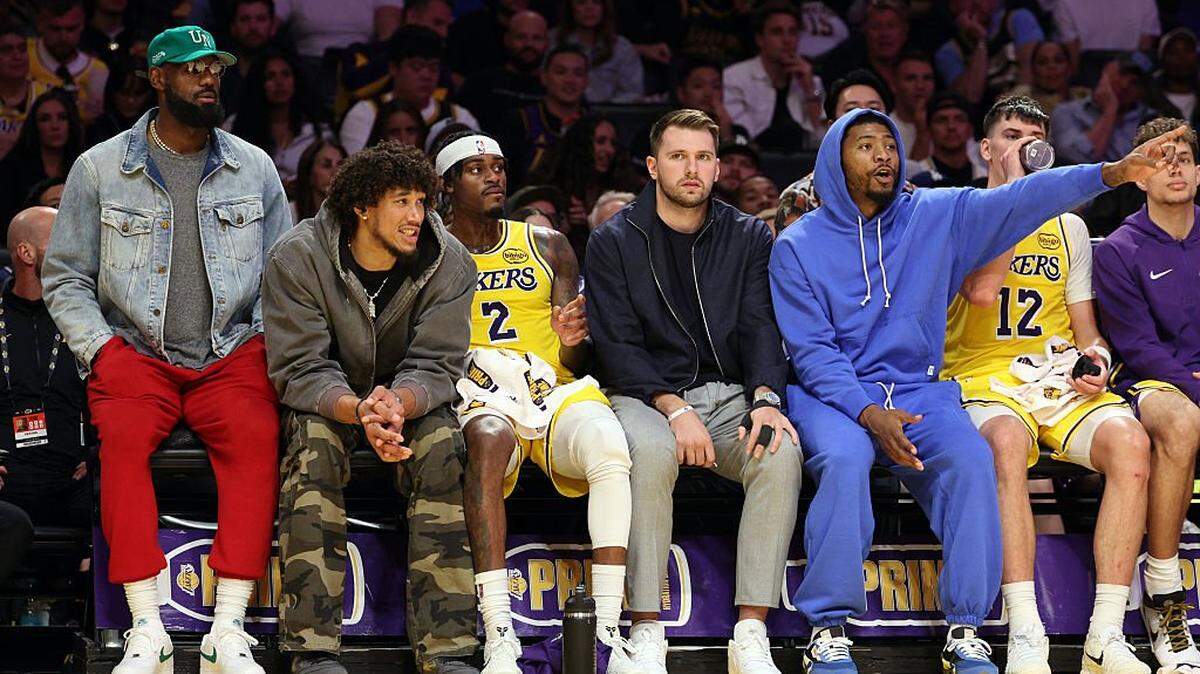 El astro LeBron James (izq.) mira un partido de los Lakers ante los Trail Blazers de Portland junto con otros jugadores del equipo, el  27 de octubre de 2025 en Los Angeles, California.