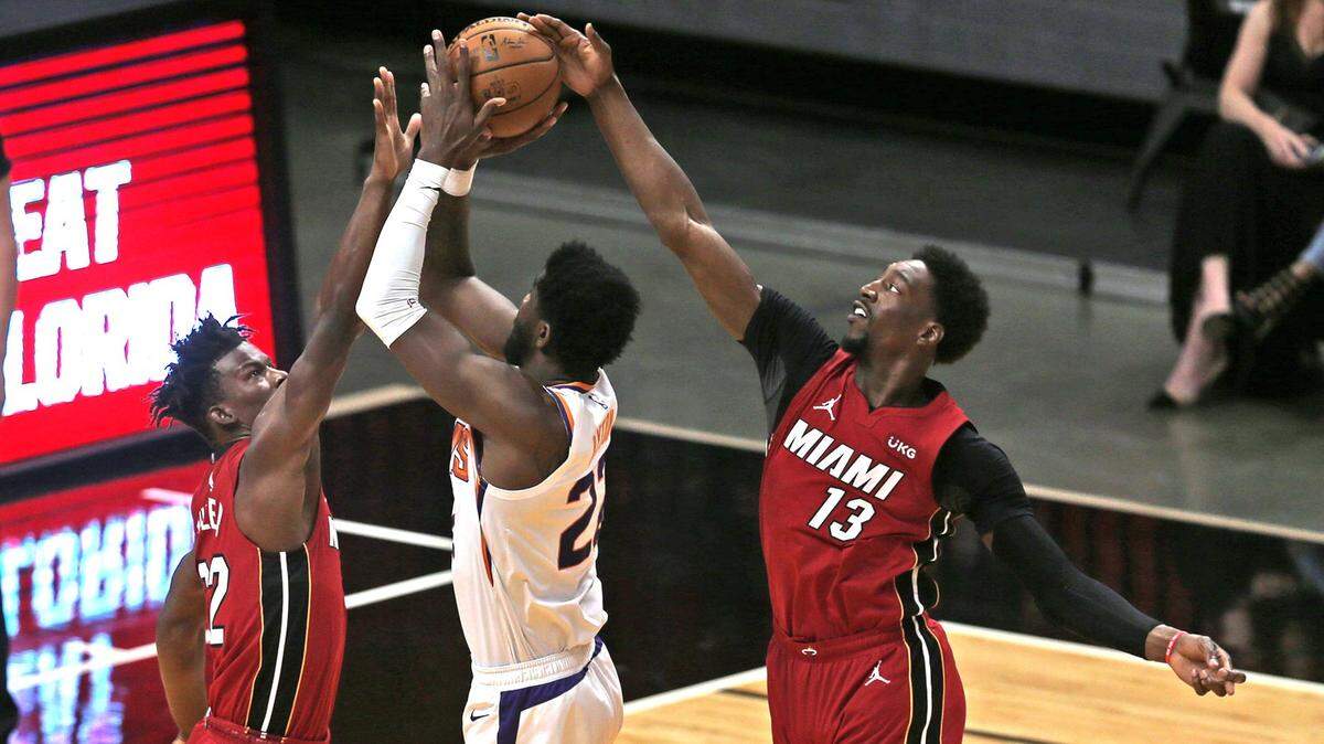 Los jugadores del Heat Jimmy Butler (22) y Bam Adebayo (13) tratan de bloquear el tiro de Deandre Ayton, de los Suns de Phoenix, en el primer cuarto del partido celebrado el 23 de marzo de 2021 en Miami.