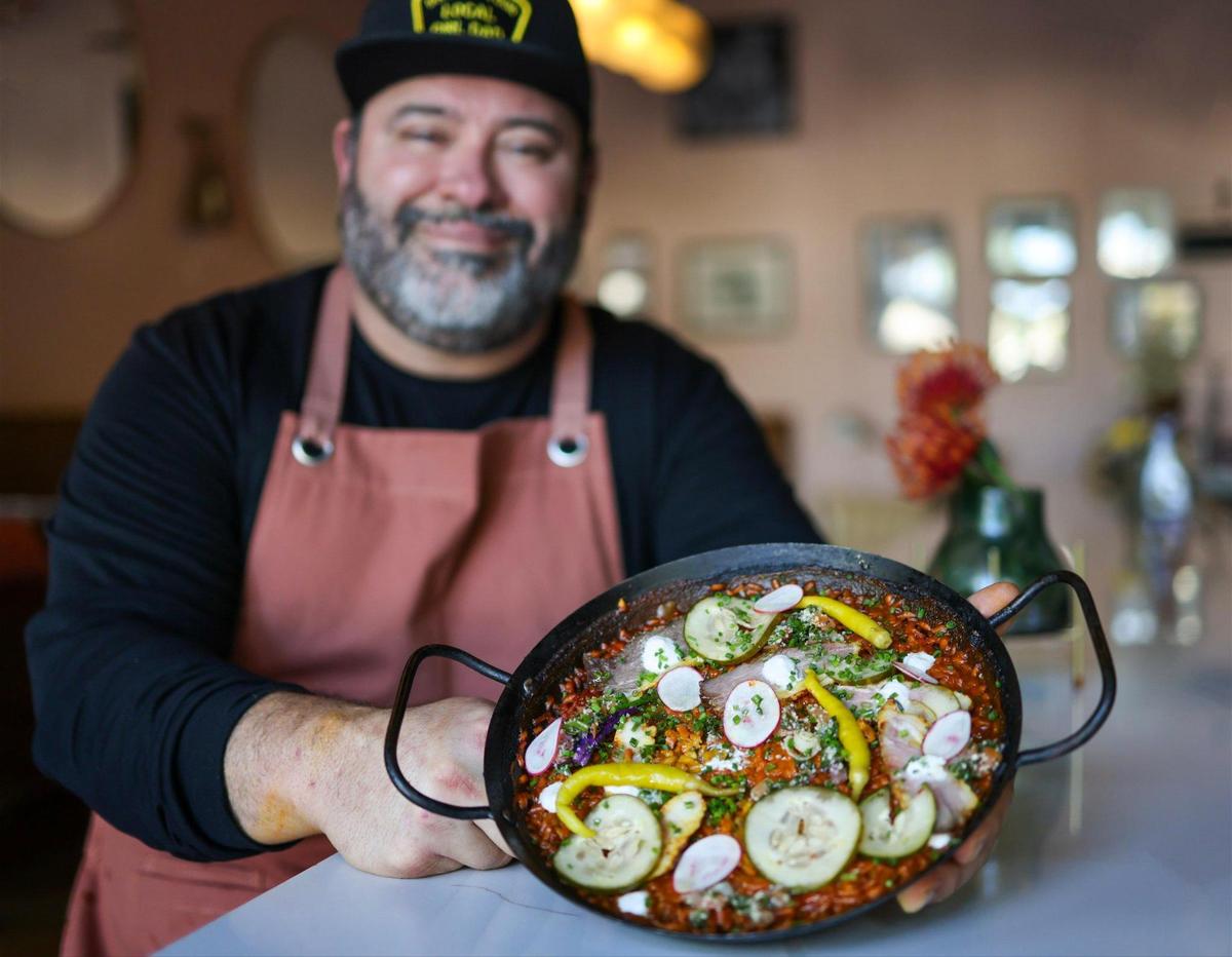 Jorgie Ramos sostiene una sartén con paella ahumada en su restaurante Bar Bella en South Miami.