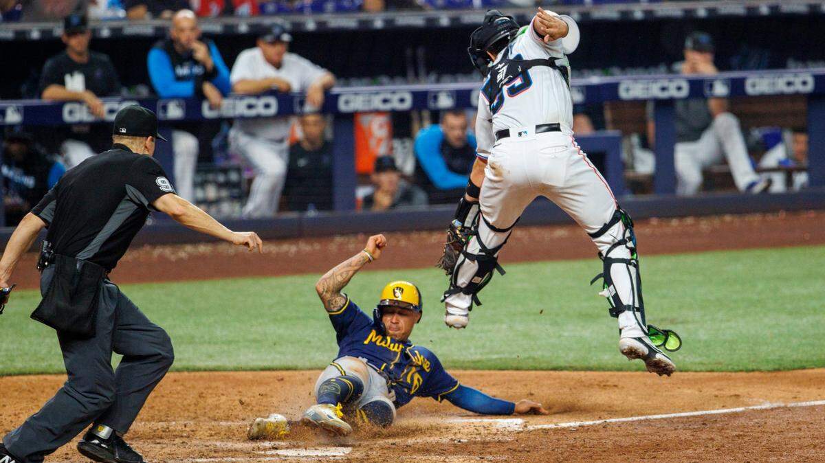 El segunda base de los Cerveceros de Milwaukee, Kolten Wong (16), anota cuando el receptor de los Marlins de Miami, Payton Henry (59), no puede tocarlo a tiempo en la octava entrada de un juego en el LoanDepot Par,k el domingo 15 de mayo de 2022.