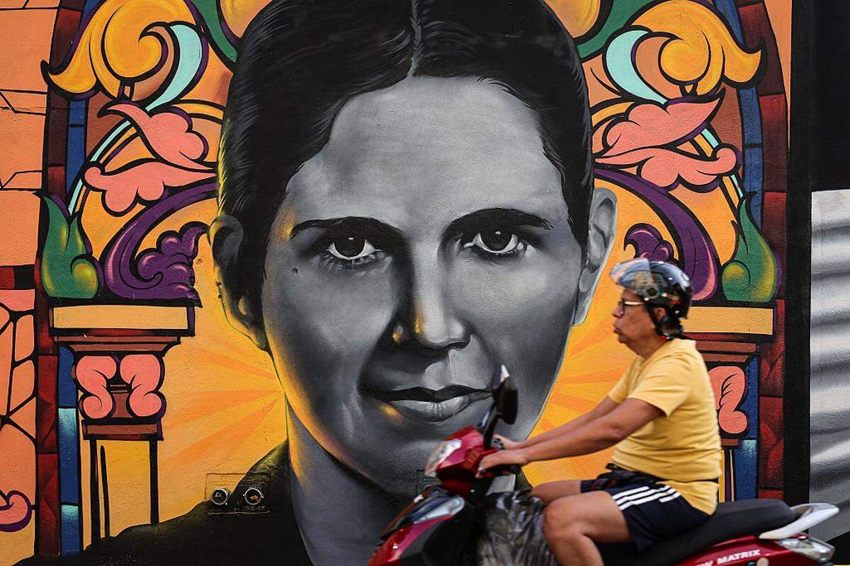 CARACAS, VENEZUELA - OCTOBER 18: Motorcyclist rides in front of Blessed Carmen Rendiles MartÃnez' mural painted in honor of the canonization of Blessed JosÃ© Gregorio HernÃ(degrees)ndez and Blessed Carmen Rendiles MartÃnez on October 18, 2025 in Caracas, Venezuela. Mother Carmen and JosÃ© Gregorio HernÃ(degrees)ndez Cisneros, a doctor, scientist, known as the "Doctor of the Poor" will be canonized by Pope Leo XIV during a solemn Mass at St. Peter's Basilica on October 19, 2025, and will be Venezuela's first two saints. (Photo by Jesus Vargas/Getty Images)