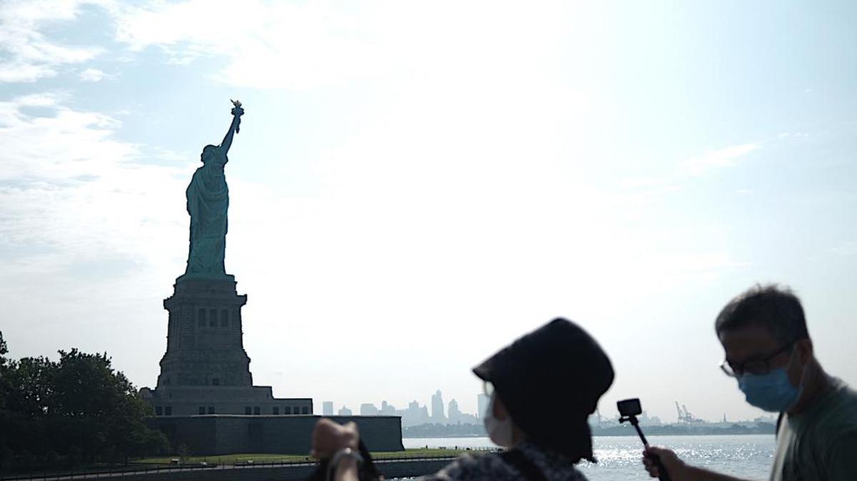 Los turistas toman fotos de la Isla de la Libertad reabierta con la Estatua de la Libertad frente al horizonte del Bajo Manhattan el 20 de julio de 2020 en la ciudad de Nueva York. - Solo unos pocos turistas visitaron el monumento reabierto cuando la ciudad de Nueva York se muda a la Fase 4 del bloqueo de Coronavirus. (Foto de Johannes EISELE / AFP) (Foto de JOHANNES EISELE / AFP a través de Getty Images)