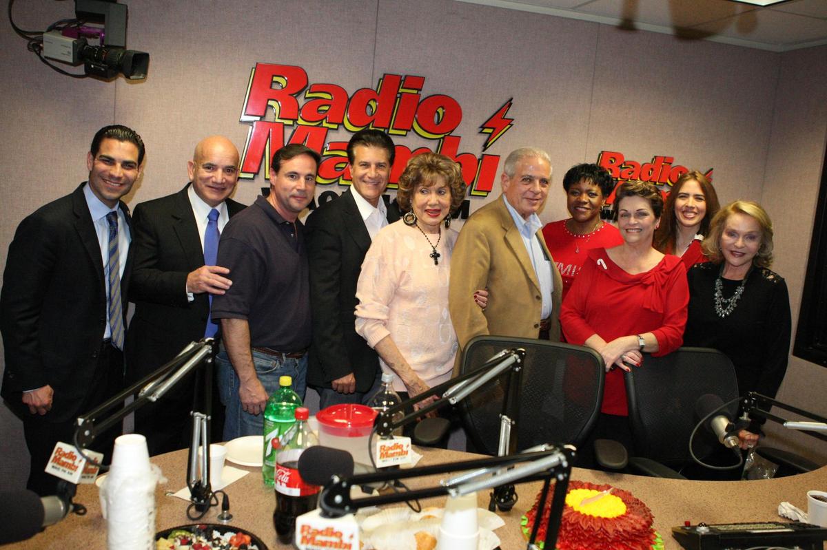 Martha Flores, “La Reina de la Noche”, en la cabina de Radio Mambí con políticos y figuras públicas de Miami en una foto de archivo. Flores, fallecida en el 2020, fue una de las locutoras que brindó un servicio comunitario desde las ondas radiales de la emisora que ha sido vendida por TelevisaUnivisión a una compañía de corte liberal.