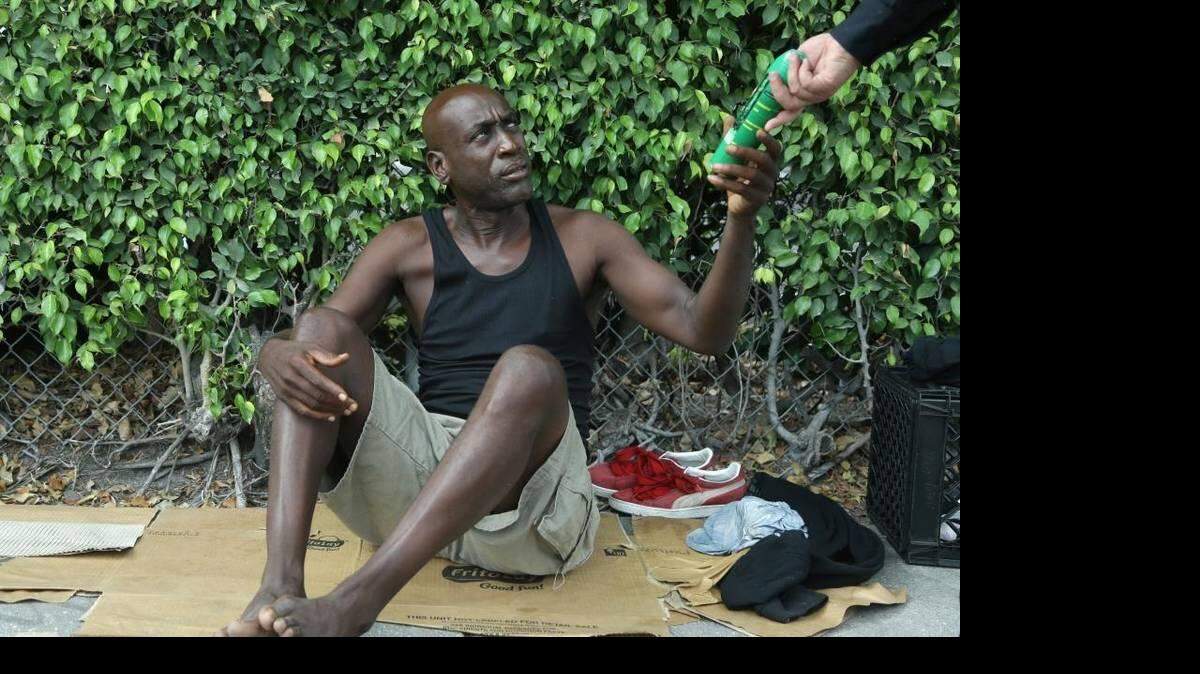 Lorenzo Ward, de 45 años y sin hogar, recibe un repelente de insectos por parte del agente de policía de Miami James Bernat en Wynwood el 2 de agosto de 2016.  Lynne Sladky AP