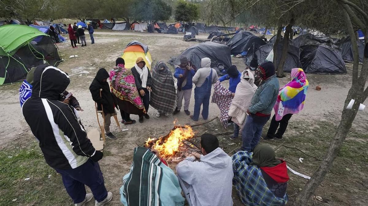 Migrantes se paran en el clima frío alrededor de una fogata en un campamento improvisado en la frontera entre Estados Unidos y México en Matamoros, México, el 23 de diciembre de 2022. (AP Foto/ Fernando Llano, Archivo)