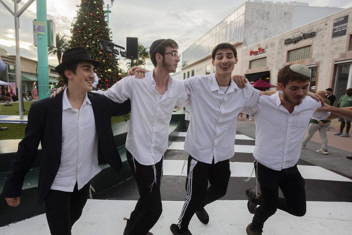 De izquierda a derecha: Shimmy Rubashkin, de 15 años, Yosef Novack, de 18 años, Yakov Motorca, de 17 años, y Dovie Givre, de 19 años, bailan durante el festival que marca la primera noche de Januká en Lincoln Road en Miami Beach, Florida, el 14 de diciembre de 2025.