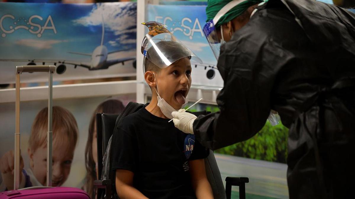 Un trabajador de salud recolecta una muestra de hisopo para una prueba de COVID-19 de un niño en el Aeropuerto Internacional José Martí mientras se reanudan los vuelos comerciales en La Habana el 15 de noviembre de 2020.
