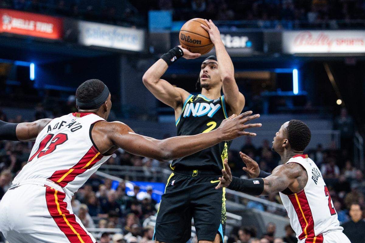El jugador de los Pacers Andrew Nembhard (centro) tira al aro ante la marca de Terry Rozier (der.) y Bam Adebayo, del Heat de Miami, en el partido celebrado el 7 de abril de 2024 en Indiana.