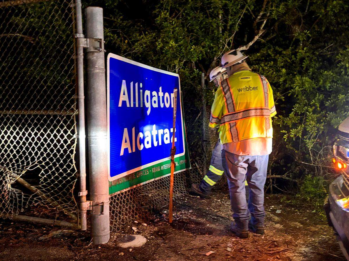Dos trabajadores instalaron un nuevo cartel con el texto Alligator Alcatraz en la entrada del lugar, encima del antiguo letrero del Aeropuerto de Entrenamiento y Transición Dade-Collier en el sitio ubicado en Ochopee, Florida, en la noche del miércoles 2 de julio de 2025.
