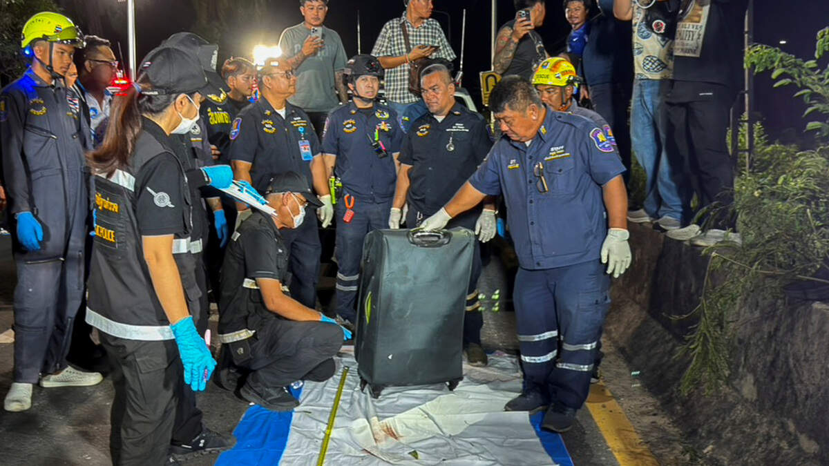 Personal de rescate y técnicos forenses con una maleta, en la que la policía encontró posteriormente el cuerpo de una joven tailandesa de 17 años, para su examen, tras ser recuperado de una zona cubierta de hierba cerca de una vía férrea en la ciudad de Pattaya, Tailandia, el sábado 27 de junio de 2026.