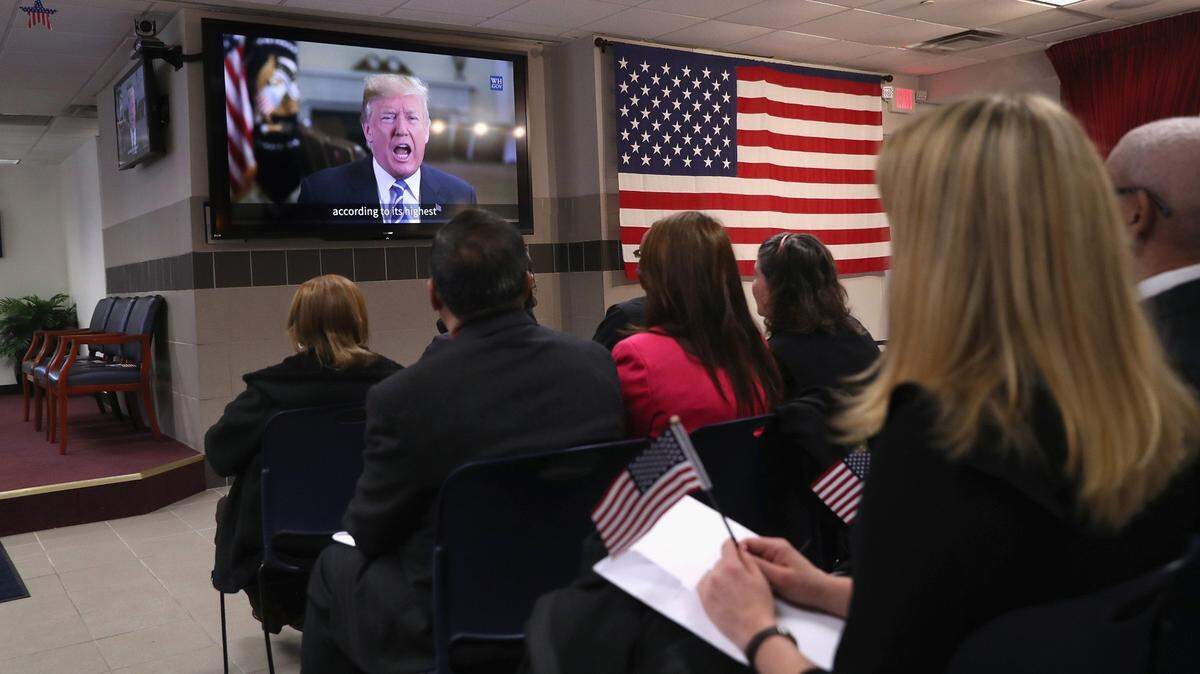 Nuevos ciudadanos de Estados Unidos ven un video del presidente Donald Trump dándoles la bienvenida en una ceremonia de naturalización en Nueva York, el 2 de febrero. La Solicitud de Naturalización es uno de los formularios que pueden pagarse con tarjeta de crédito.