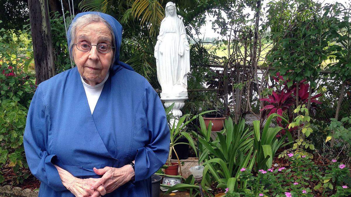 Sister Hilda Alonso, founder of the Daughters of Charity of St. Vincent de Paul in Miami, poses in front of a statue of Our Lady of the Miraculous Medal, a Marian devotion encouraged by the Daughters of Charity, in her convent’s courtyard in Flagami, in 2014.