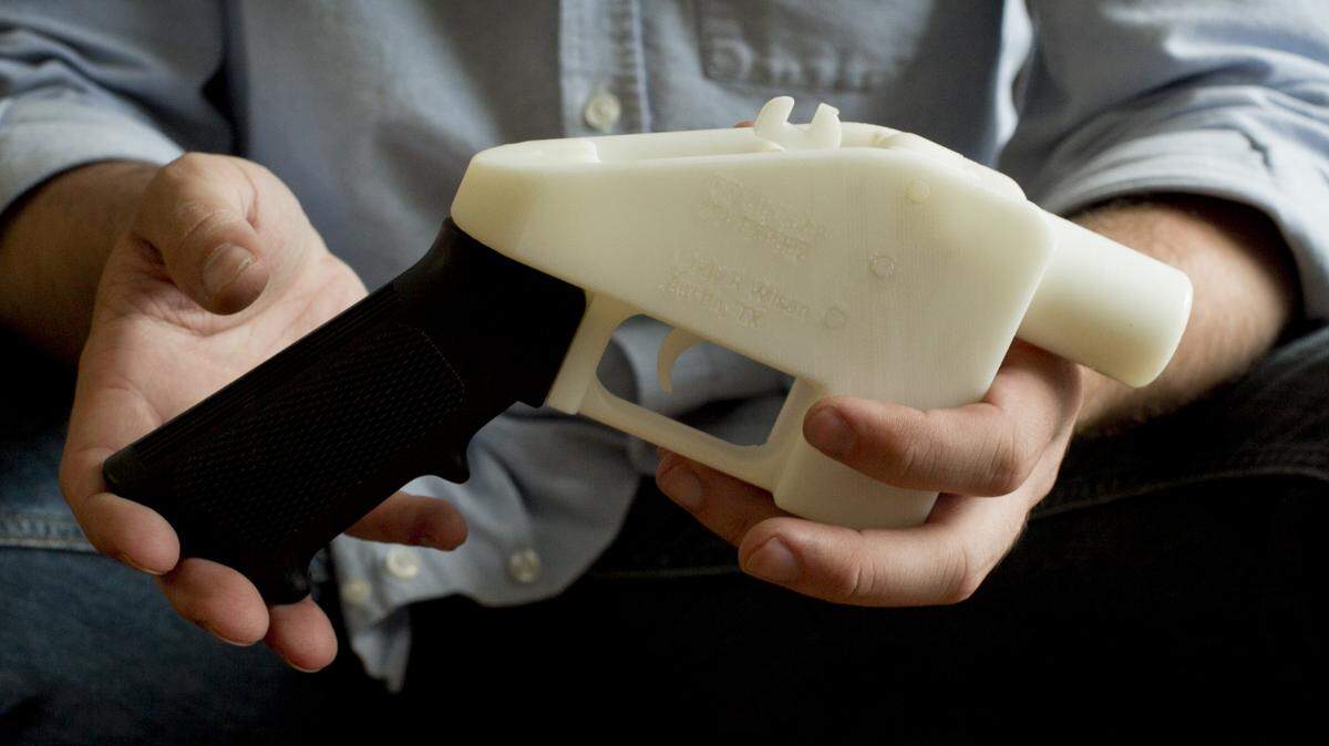 Cody Wilson holds a gun he made on a 3D printer in his Texas home.