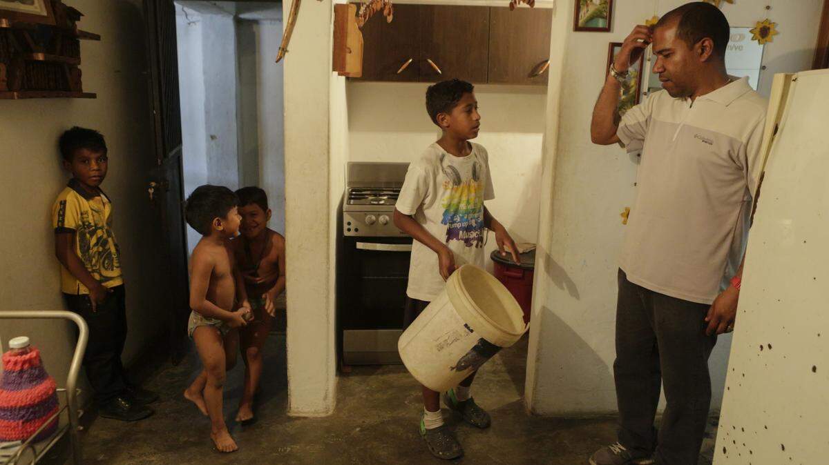 Un hombre habla con niños en su casa, en el barrio de Petare, el 4 de abril de 2019 en Caracas, Venezuela. Desde el 7 de marzo, Venezuela ha estado sufriendo apagones intermitentes que afectaron el suministro de agua. La gente tiene que recoger el agua de las cascadas y tuberías y llevarla a sus hogares. Esta agua, no siempre apta para el consumo humano, se utiliza para beber, cocinar y bañarse.