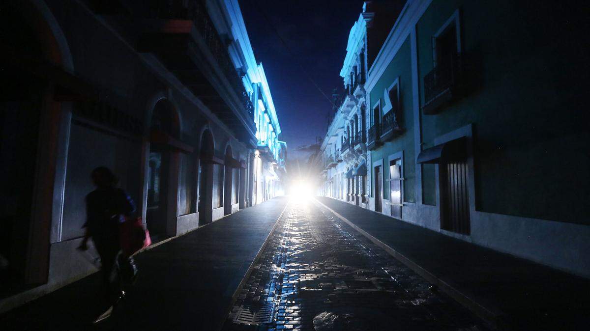 Una mujer camina en una calle oscura en el turístico barrio del Viejo San Juan, el 13 de octubre de 2017 en San Juan, Puerto Rico.