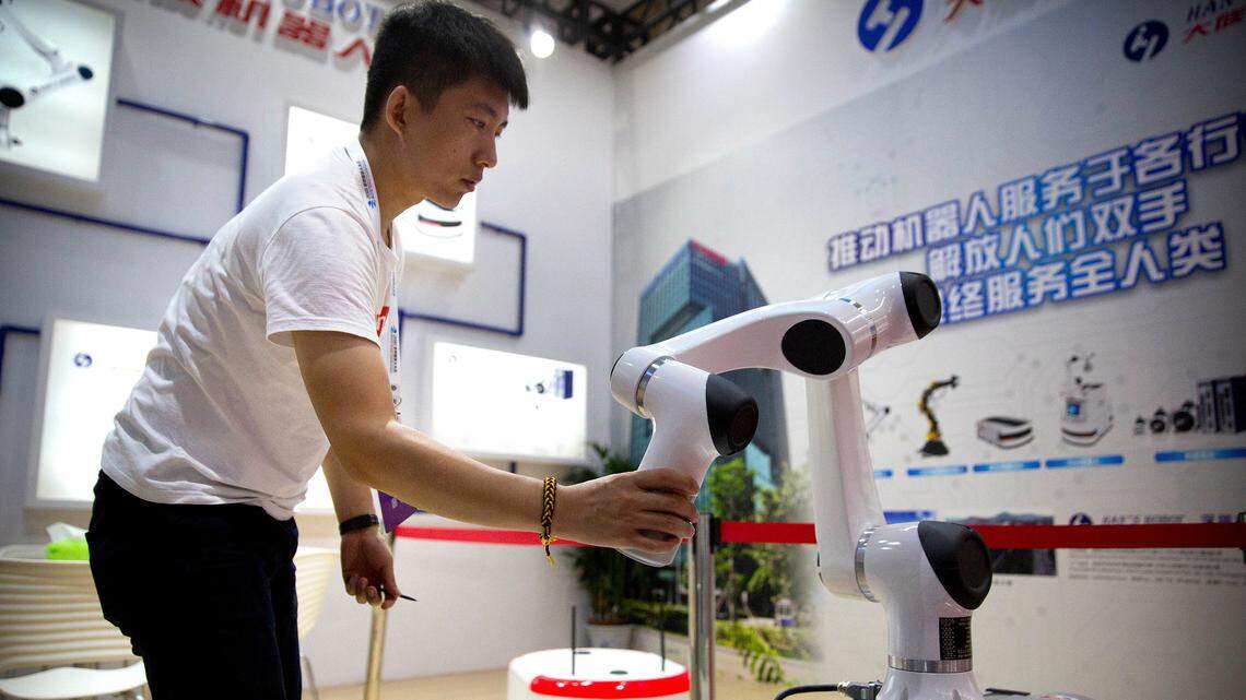Un asistente al evento World Robot Conference en Pekín examina un brazo robótico del fabricante chino Han’s Robots, en agosto del 2018.
