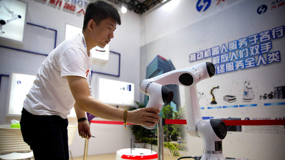 Un asistente al evento World Robot Conference en Pekín examina un brazo robótico del fabricante chino Han’s Robots, en agosto del 2018.