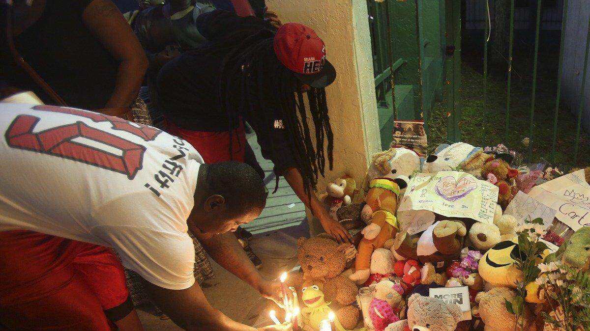 Reginald Brooks, izquierda, y Nay Akins, encienden velas en honor a King Carter, de 6 años,  durante una manifestación el jueves, 25 de febrero de 2016. 