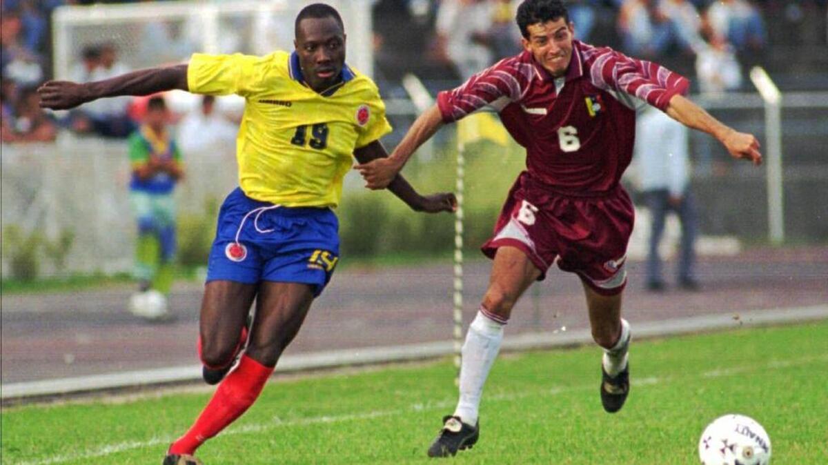 El jugador colombiano Freddy Rincón, izquierda, lucha por el balón con Elvis Martínez de Venezuela durante un partido de clasificación de Francia ’98 en San Cristóbal, Venezuela, el 15 de diciembre de 1996. (Foto AP/José Caruci, archivo)