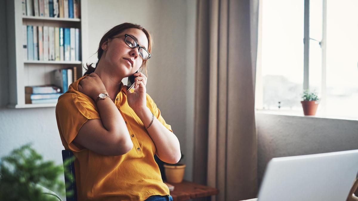 Cropped shot of an attractive young businesswoman sitting alone in her home office and feeling stressed while using her cellphone