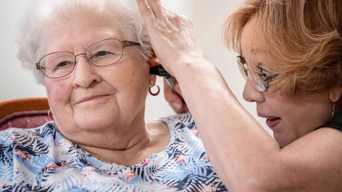 Janie York examina el oído de Elaine Martin en Silver Ridge Assisted Living, en Gretna, Nebraska, en agosto. Martin tenía bastante cera en sus oídos, antes que York le realizara una limpieza y comenzara a usar audífonos. Ahora, York le limpia los oídos a Martin con regularidad.