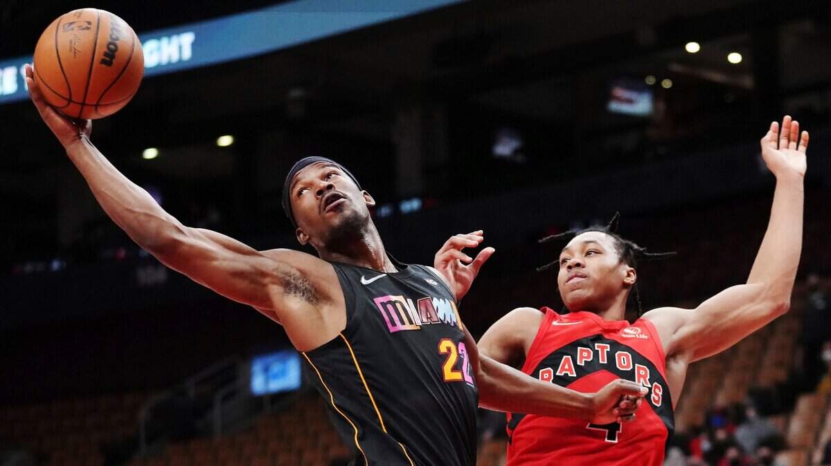 El jugador del Heat Jimmy Butler (22) consigue la pelota ante la marca de Scottie Barnes, de los Raptors, en el partido celebrado el 1ro de febrero de 2022 en Toronto.