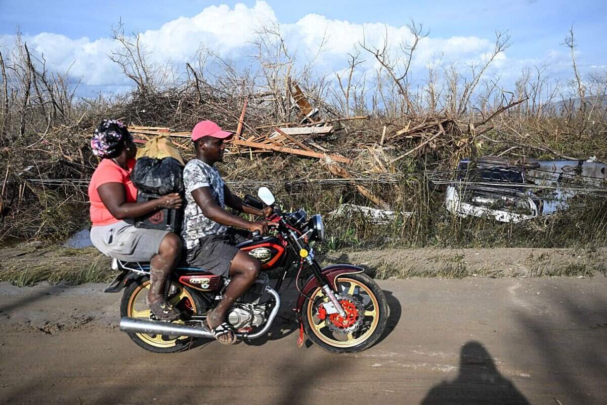 Residentes pasan en sus vehículos junto a los escombros que cubren la orilla de la carretera tras el paso del huracán Melissa, en Black River, St. Elizabeth, Jamaica, el 29 de octubre de 2025.