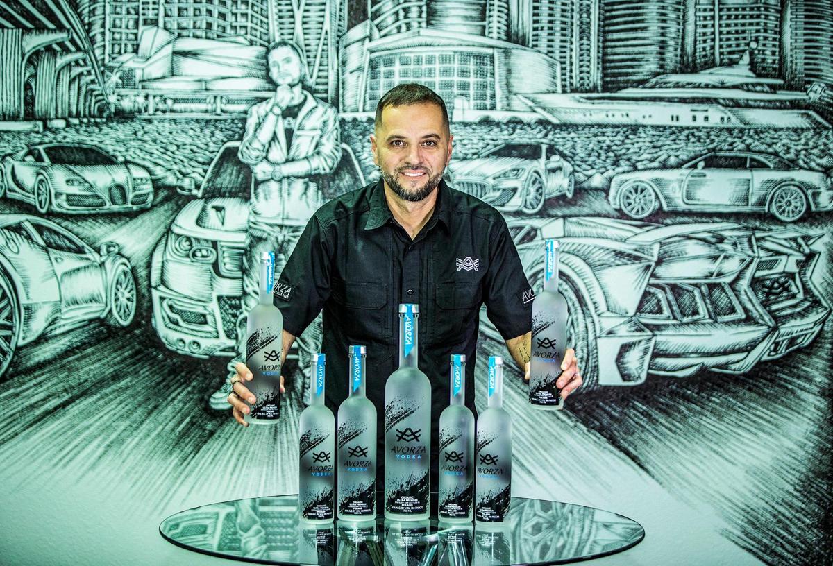 El empresario cubano Alex Vega, dueño de The Auto Firm, muestra las botellas de su vodka, que nombró Avorza, como las piezas de auto que lo han hecho famoso. Los pedidos del vodka, que se produce en Polonia, han aumentado desde que los consumidores rechazan el vodka ruso por vincularlo con la invasión de Putin a Ucrania.