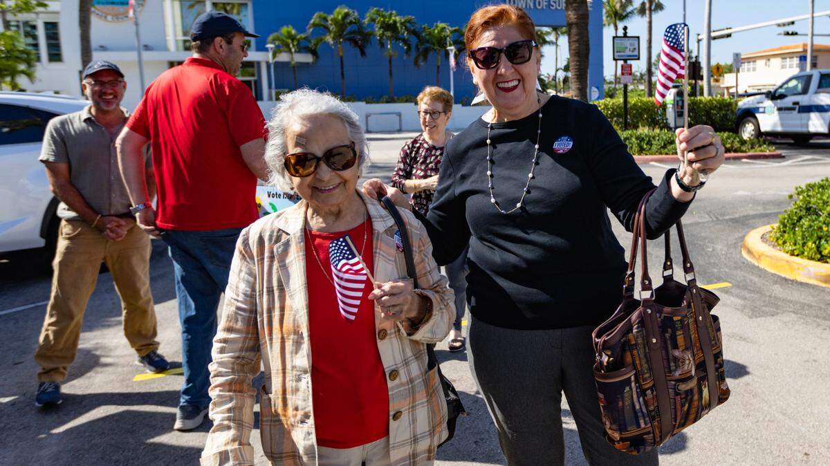 María Rosa Benítez, de 94 años, y su amiga Mariana Reyes, de 67, caminan después de emitir su voto durante las elecciones primarias presidenciales y locales en el condado de Miami-Dade, en el Ayuntamiento de Surfside, el martes 19 de marzo de 2024.