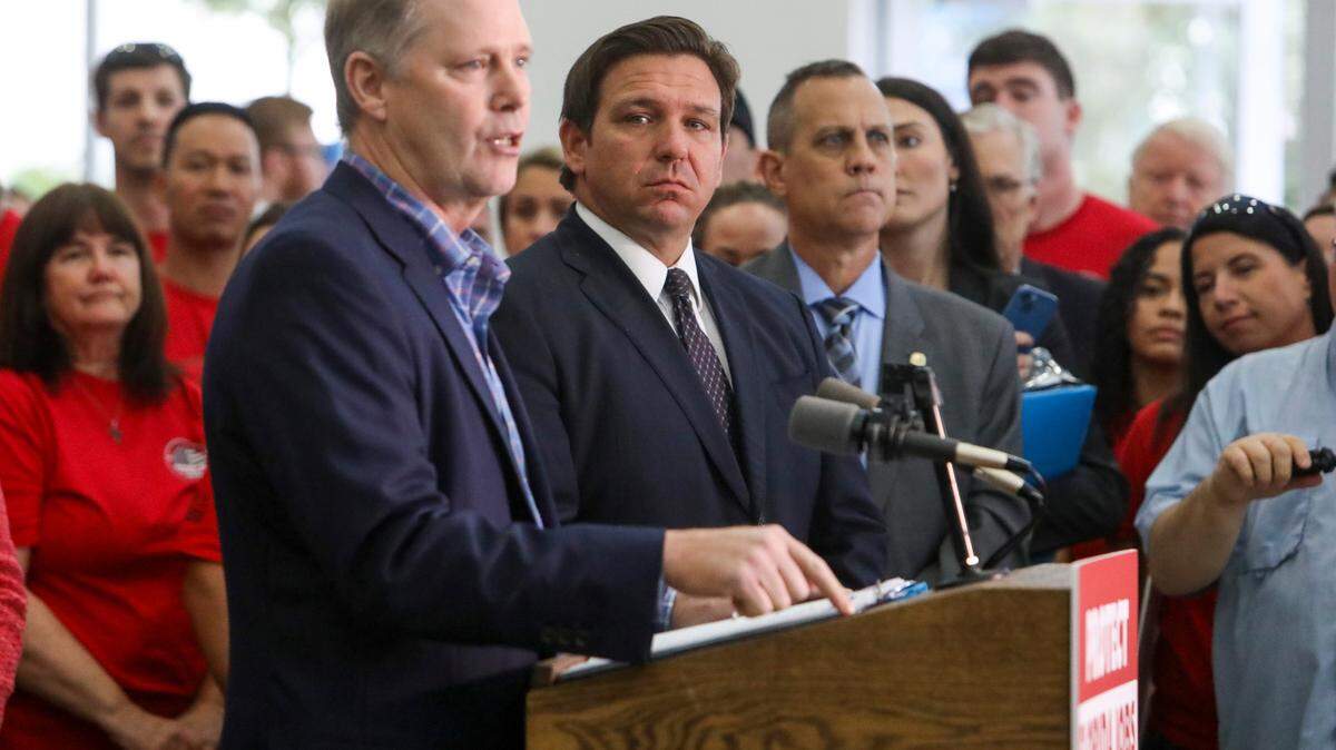 El entonces presidente del Senado, Wilton Simpson, habla mientras el gobernador Ron DeSantis escucha cerca antes de firmar leyes para limitar los mandatos de vacunas contra el COVID-19 en empleados del sector privado, del gobierno estatal y de los distritos escolares, en Brandon, el jueves 18 de noviembre de 2021.